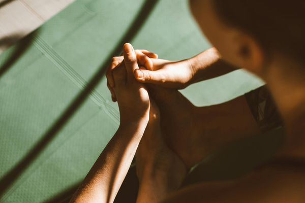 Close-up of hands in a mindful gesture on a yoga mat.